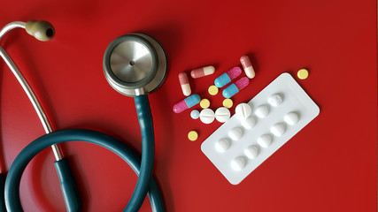Medication and pharmaceutical drugs and stethoscope on red background. Stethoscope for diagnosis and medicine drug for treatment disease. Medical technology and hospital care concept.