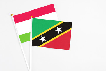 Saint Kitts And Nevis and Tajikistan stick flags on white background. High quality fabric, miniature national flag. Peaceful global concept.White floor for copy space.