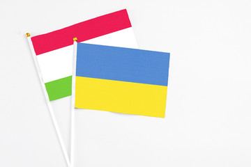 Ukraine and Tajikistan stick flags on white background. High quality fabric, miniature national flag. Peaceful global concept.White floor for copy space.