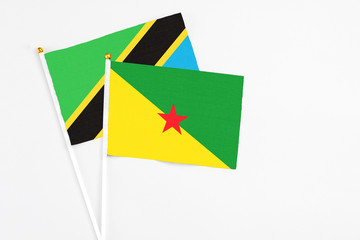French Guiana and Tanzania stick flags on white background. High quality fabric, miniature national flag. Peaceful global concept.White floor for copy space.