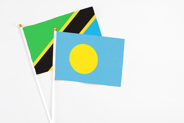 Palau and Tanzania stick flags on white background. High quality fabric, miniature national flag. Peaceful global concept.White floor for copy space.