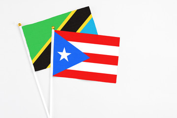 Fototapeta premium Puerto Rico and Tanzania stick flags on white background. High quality fabric, miniature national flag. Peaceful global concept.White floor for copy space.
