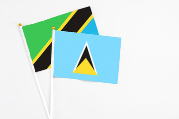 Saint Lucia and Tanzania stick flags on white background. High quality fabric, miniature national flag. Peaceful global concept.White floor for copy space.