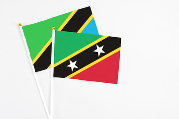 Saint Kitts And Nevis and Tanzania stick flags on white background. High quality fabric, miniature national flag. Peaceful global concept.White floor for copy space.