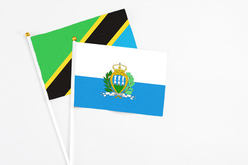 San Marino and Tanzania stick flags on white background. High quality fabric, miniature national flag. Peaceful global concept.White floor for copy space.