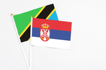 Serbia and Tanzania stick flags on white background. High quality fabric, miniature national flag. Peaceful global concept.White floor for copy space.
