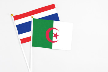 Algeria and Thailand stick flags on white background. High quality fabric, miniature national flag. Peaceful global concept.White floor for copy space.