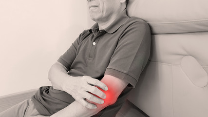 Elderly man suffering from elbow pain with painful facial expression. Elbow pain may cause from muscle strain, tendinitis, ligament sprain, fracture, bursitis or arthritis disorder. medical symptom.