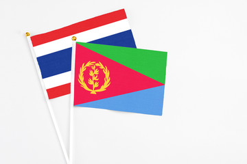 Eritrea and Thailand stick flags on white background. High quality fabric, miniature national flag. Peaceful global concept.White floor for copy space.