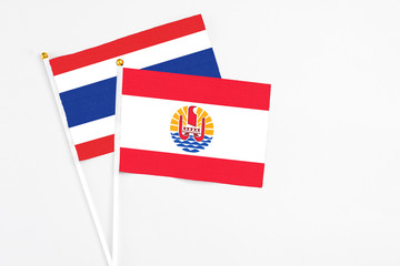 French Polynesia and Thailand stick flags on white background. High quality fabric, miniature national flag. Peaceful global concept.White floor for copy space.