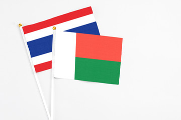 Madagascar and Thailand stick flags on white background. High quality fabric, miniature national flag. Peaceful global concept.White floor for copy space.