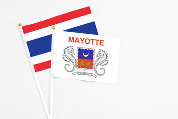 Mayotte and Thailand stick flags on white background. High quality fabric, miniature national flag. Peaceful global concept.White floor for copy space.