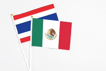 Mexico and Thailand stick flags on white background. High quality fabric, miniature national flag. Peaceful global concept.White floor for copy space.