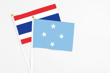 Micronesia and Thailand stick flags on white background. High quality fabric, miniature national flag. Peaceful global concept.White floor for copy space.
