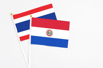Paraguay and Thailand stick flags on white background. High quality fabric, miniature national flag. Peaceful global concept.White floor for copy space.