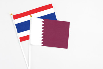 Fototapeta na wymiar Qatar and Thailand stick flags on white background. High quality fabric, miniature national flag. Peaceful global concept.White floor for copy space.