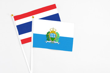 San Marino and Thailand stick flags on white background. High quality fabric, miniature national flag. Peaceful global concept.White floor for copy space.