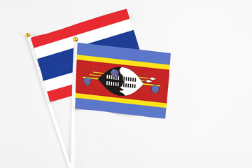 Swaziland and Thailand stick flags on white background. High quality fabric, miniature national flag. Peaceful global concept.White floor for copy space.