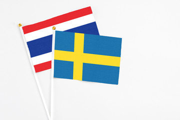 Obraz premium Sweden and Thailand stick flags on white background. High quality fabric, miniature national flag. Peaceful global concept.White floor for copy space.