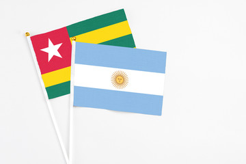 Argentina and Togo stick flags on white background. High quality fabric, miniature national flag. Peaceful global concept.White floor for copy space.