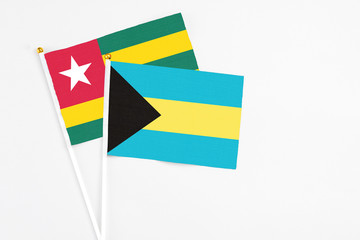 Bahamas and Togo stick flags on white background. High quality fabric, miniature national flag. Peaceful global concept.White floor for copy space.