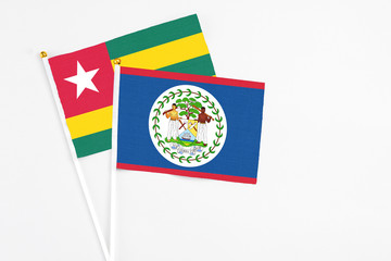 Belize and Togo stick flags on white background. High quality fabric, miniature national flag. Peaceful global concept.White floor for copy space.