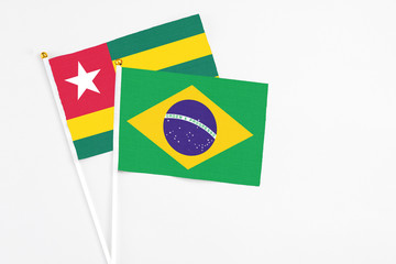 Brazil and Togo stick flags on white background. High quality fabric, miniature national flag. Peaceful global concept.White floor for copy space.