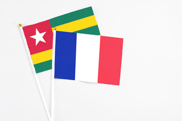Fototapeta premium France and Togo stick flags on white background. High quality fabric, miniature national flag. Peaceful global concept.White floor for copy space.
