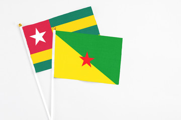 French Guiana and Togo stick flags on white background. High quality fabric, miniature national flag. Peaceful global concept.White floor for copy space.