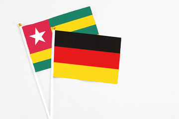 Germany and Togo stick flags on white background. High quality fabric, miniature national flag. Peaceful global concept.White floor for copy space.