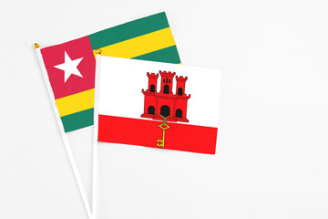 Gibraltar and Togo stick flags on white background. High quality fabric, miniature national flag. Peaceful global concept.White floor for copy space.