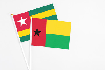 Guinea Bissau and Togo stick flags on white background. High quality fabric, miniature national flag. Peaceful global concept.White floor for copy space.