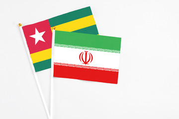 Iran and Togo stick flags on white background. High quality fabric, miniature national flag. Peaceful global concept.White floor for copy space.