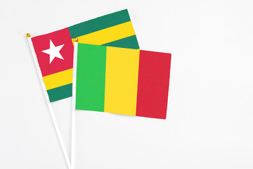 Mali and Togo stick flags on white background. High quality fabric, miniature national flag. Peaceful global concept.White floor for copy space.