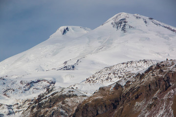 Fototapeta na wymiar Mount Elbrus in the month of November. The mountains are covered with white snow. At the foot of mount Elbrus. Mountains for snowboarders and mountain skiers.