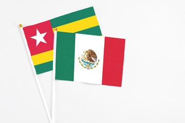 Mexico and Togo stick flags on white background. High quality fabric, miniature national flag. Peaceful global concept.White floor for copy space.