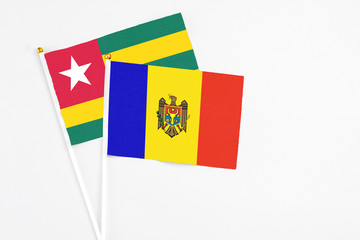 Moldova and Togo stick flags on white background. High quality fabric, miniature national flag. Peaceful global concept.White floor for copy space.