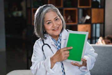 senior doctor holding tab and show screen of tab to the camera