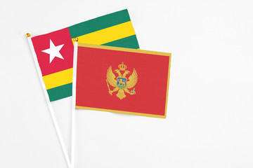 Montenegro and Togo stick flags on white background. High quality fabric, miniature national flag. Peaceful global concept.White floor for copy space.