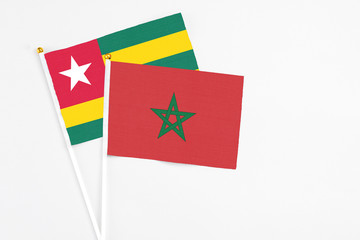 Morocco and Togo stick flags on white background. High quality fabric, miniature national flag. Peaceful global concept.White floor for copy space.