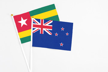 Fototapeta premium New Zealand and Togo stick flags on white background. High quality fabric, miniature national flag. Peaceful global concept.White floor for copy space.