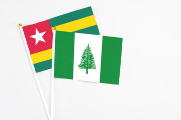 Norfolk Island and Togo stick flags on white background. High quality fabric, miniature national flag. Peaceful global concept.White floor for copy space.
