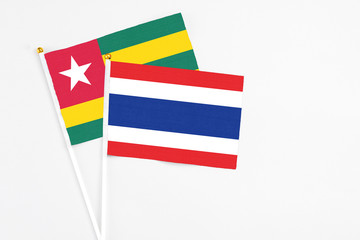 Thailand and Togo stick flags on white background. High quality fabric, miniature national flag. Peaceful global concept.White floor for copy space.