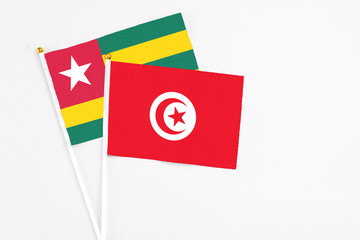 Tunisia and Togo stick flags on white background. High quality fabric, miniature national flag. Peaceful global concept.White floor for copy space.