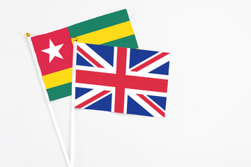 Fototapeta premium United Kingdom and Togo stick flags on white background. High quality fabric, miniature national flag. Peaceful global concept.White floor for copy space.