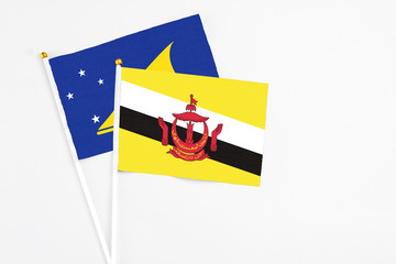 Naklejka premium Brunei and Tokelau stick flags on white background. High quality fabric, miniature national flag. Peaceful global concept.White floor for copy space.