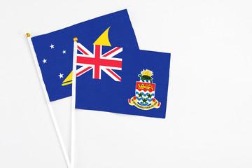 Fototapeta premium Cayman Islands and Tokelau stick flags on white background. High quality fabric, miniature national flag. Peaceful global concept.White floor for copy space.
