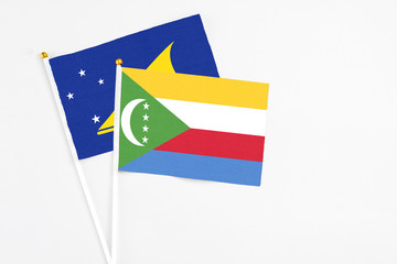 Comoros and Tokelau stick flags on white background. High quality fabric, miniature national flag. Peaceful global concept.White floor for copy space.