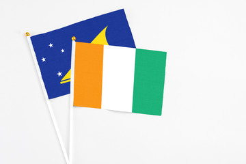 Cote D'Ivoire and Tokelau stick flags on white background. High quality fabric, miniature national flag. Peaceful global concept.White floor for copy space.