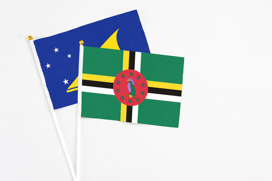 Dominica and Tokelau stick flags on white background. High quality fabric, miniature national flag. Peaceful global concept.White floor for copy space.